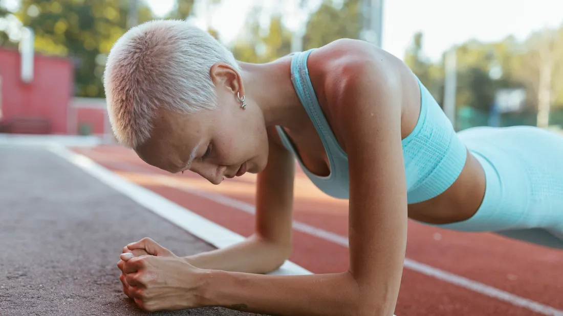 Coureur à quatre pattes levant bras et genou opposés, dos plat sur un tapis de sport